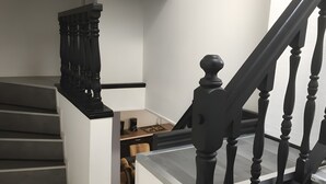 A staircase with black balusters, a wooden desk with a chair, and a coffee maker. - Charming Cottage in a Converted Farmhouse with Wi-Fi (Vendin-le-Vieil)