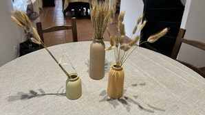 A round table with three vases containing dried plants, a wooden chair, and a dining area in the background. - Charming Cottage in a Converted Farmhouse with Wi-Fi (Vendin-le-Vieil)