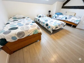 A room with three wooden beds, each with a circular-patterned bedspread. There is a radiator on the wall and a small table with a lamp. - Charming Cottage in a Converted Farmhouse with Wi-Fi (Vendin-le-Vieil)