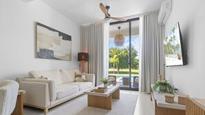 A modern living room with a sofa, coffee table, and a TV on a stand. - Cocotal Beach Homes Punta Cana (Punta Cana)