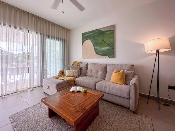 A living room with a sofa, a coffee table, a floor lamp, and a painting on the wall. - Cocotal Beach Homes Punta Cana (Punta Cana)