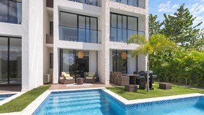 A modern two-story building with a swimming pool, outdoor seating, and lush greenery. - Cocotal Beach Homes Punta Cana (Punta Cana)