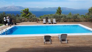 Eine Holzterrasse mit Pool, Liegestühlen und einer Kamera auf einem Stativ.