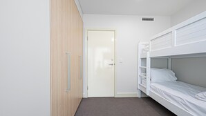 A room with a bunk bed, a wooden wardrobe, and a door. - Beachfront Serenity Glenelg (Glenelg)
