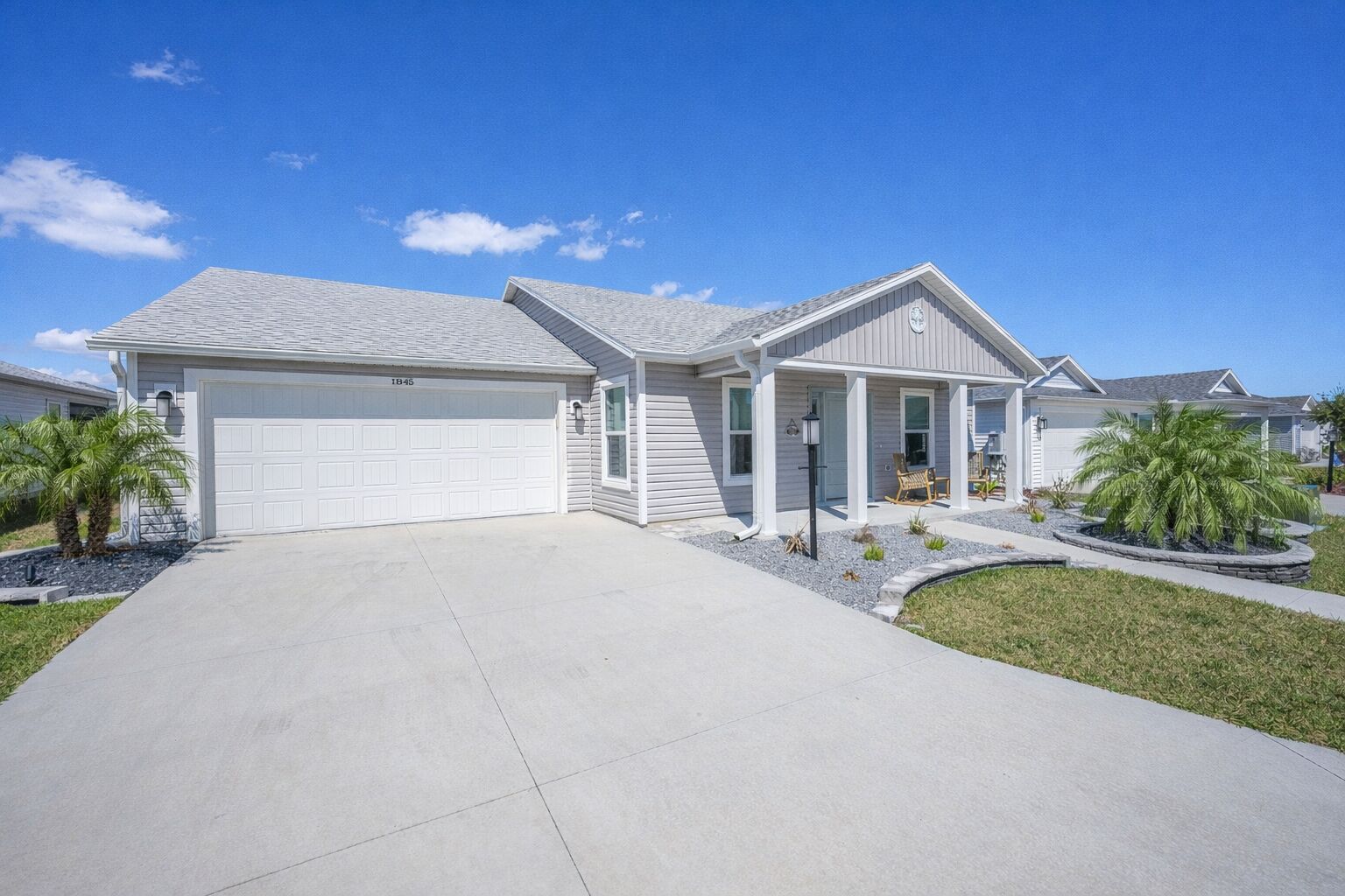 A two-story house with a garage, a covered porch, and a well-maintained lawn.
