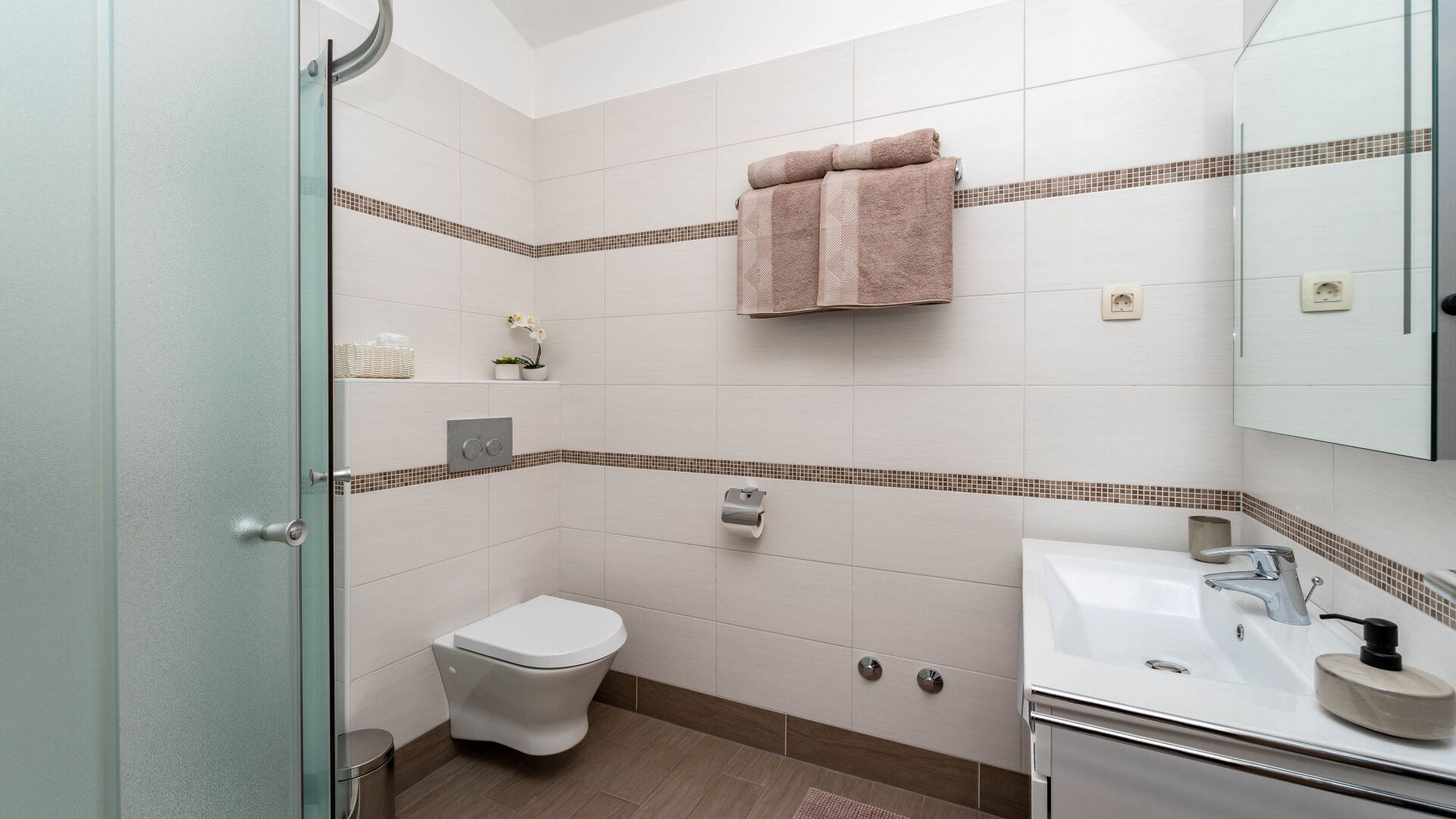 Et badeværelse med toilet, håndvask og brusekabine.