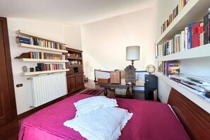 Een slaapkamer met een bed, een boekenkast, een bureau met een lamp en een wereldbol.