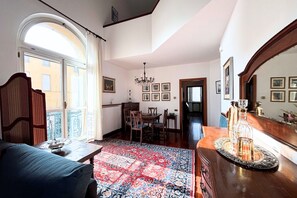 Een kamer met een eethoek, een kroonluchter en een groot raam.