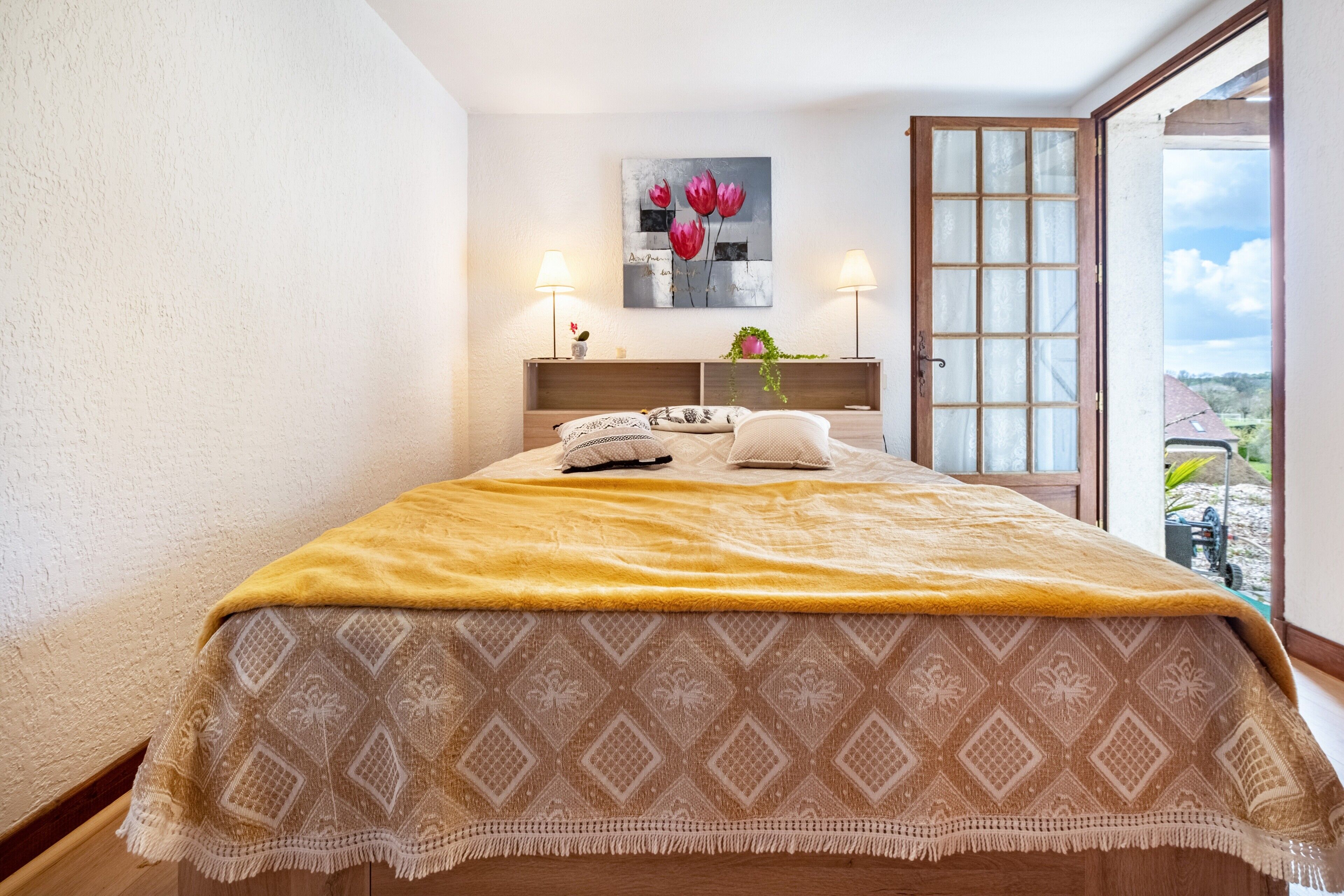 Ein Schlafzimmer mit Bett, Nachttischlampen, einem Fenster mit Blick und einem Bild an der Wand.