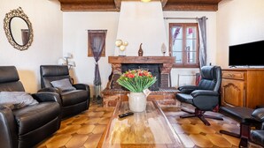 Una sala de estar con sofás de cuero, una mesa de centro de madera, una chimenea y un televisor.