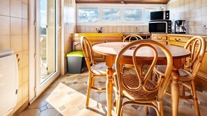 Una cocina con una mesa redonda de madera, sillas de mimbre, un microondas y una cafetera.