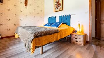 A bedroom with a bed, a nightstand, a lamp, and a door.