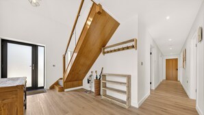 Un intérieur moderne avec un escalier en bois, un banc en bois et un couloir menant à une porte.