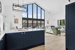 A modern kitchen with a large island, pendant lighting, and a view to the outdoors.