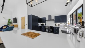 Une cuisine moderne avec des meubles de couleur sombre, un plan de travail blanc et une planche à découper en bois.