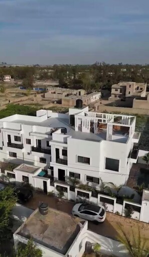 Una zona residencial moderna con edificios blancos, cielo despejado y algunos automóviles.