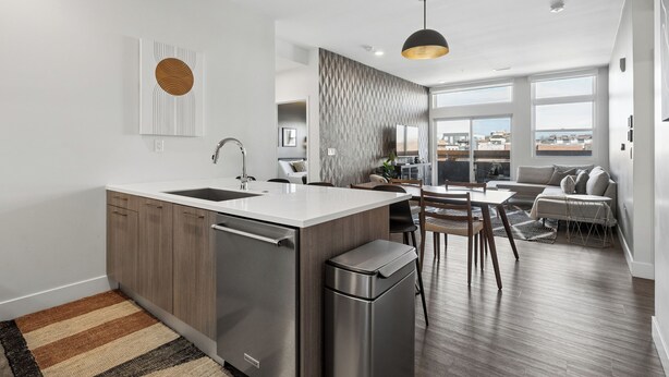A modern kitchen with a central island, stainless steel appliances, and a dining area with a view.