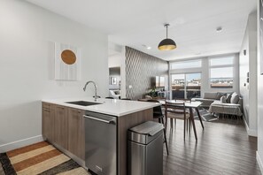 Cozinha moderna com ilha central, eletrodomésticos de aço inoxidável e área de jantar com vista.