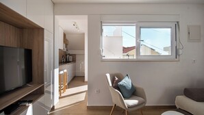 Una sala moderna con un televisor de pantalla plana, un sillón cómodo y un sofá.