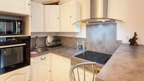 A compact kitchen with white cabinetry, a built-in oven, a microwave, a stainless steel range hood, and a modern sink. - Quiet room in shared house - Lille (Lille)