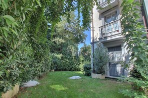 A courtyard with a lawn, a stone, and a building with balconies. - GuestHost - Modern 40m2 apartment, perfect for 4 people, located on the second floor of a building with lift.The accommodation is located in the Bocconi/Tibaldi district, a vibrant and strategic area, defined by the prestigious presence of the Bocconi Un (Milan)
