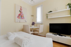 A hotel room with a bed, a TV, a desk, and a chair. - GuestHost - Modern 40m2 apartment, perfect for 4 people, located on the second floor of a building with lift.The accommodation is located in the Bocconi/Tibaldi district, a vibrant and strategic area, defined by the prestigious presence of the Bocconi Un (Milan)