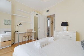 Habitación de hotel con cama, escritorio, silla y baño visible a través de una puerta abierta.