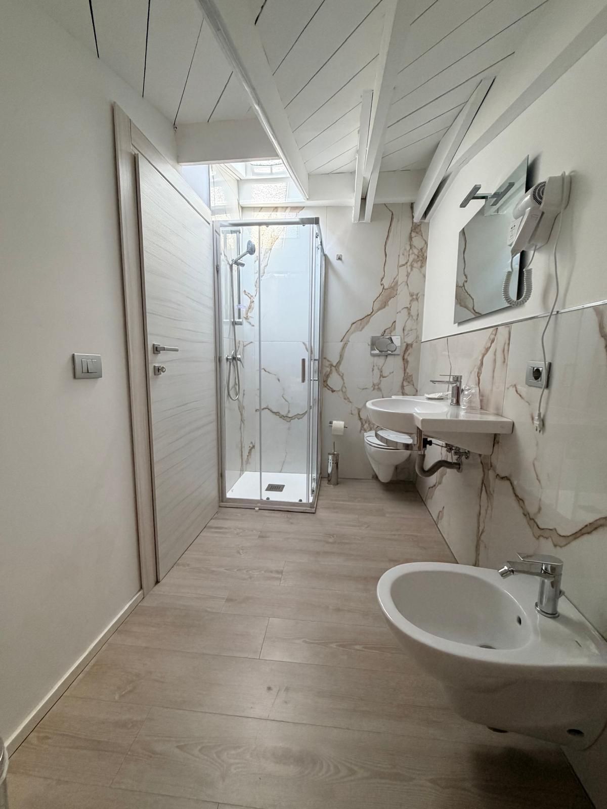 A modern bathroom with a glass-enclosed shower, a sink, and a bidet.