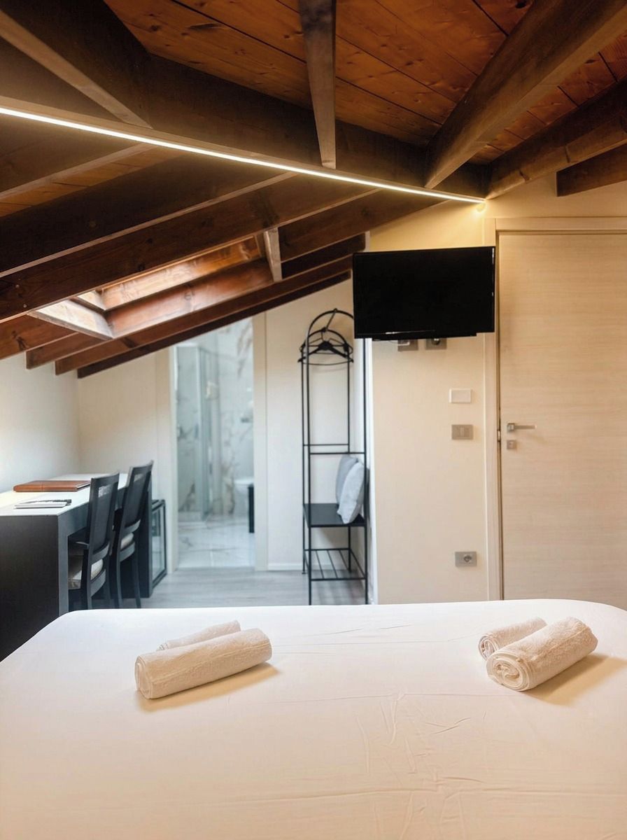 Ein Hotelzimmer mit Bett, Fernseher, Schreibtisch mit Stühlen und begehbarem Kleiderschrank.