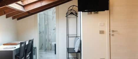 Una habitación de hotel con una cama, un televisor, un escritorio con sillas y un vestidor.