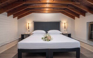Un dormitorio con una cama grande, dos mesitas de noche, un cabecero y techo de madera.