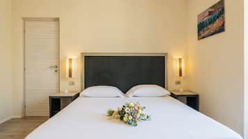 Una habitación de hotel con una cama grande, dos mesitas de noche, una puerta y un cuadro en la pared.