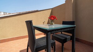 A glass-top table with wicker chairs, a vase with red flowers, and a tiled floor. - Viscuso house (Aci Castello)