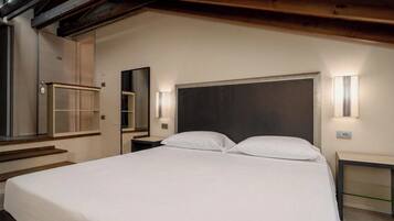 A modern bedroom with a large bed, bedside tables, a mirror, and built-in lighting.
