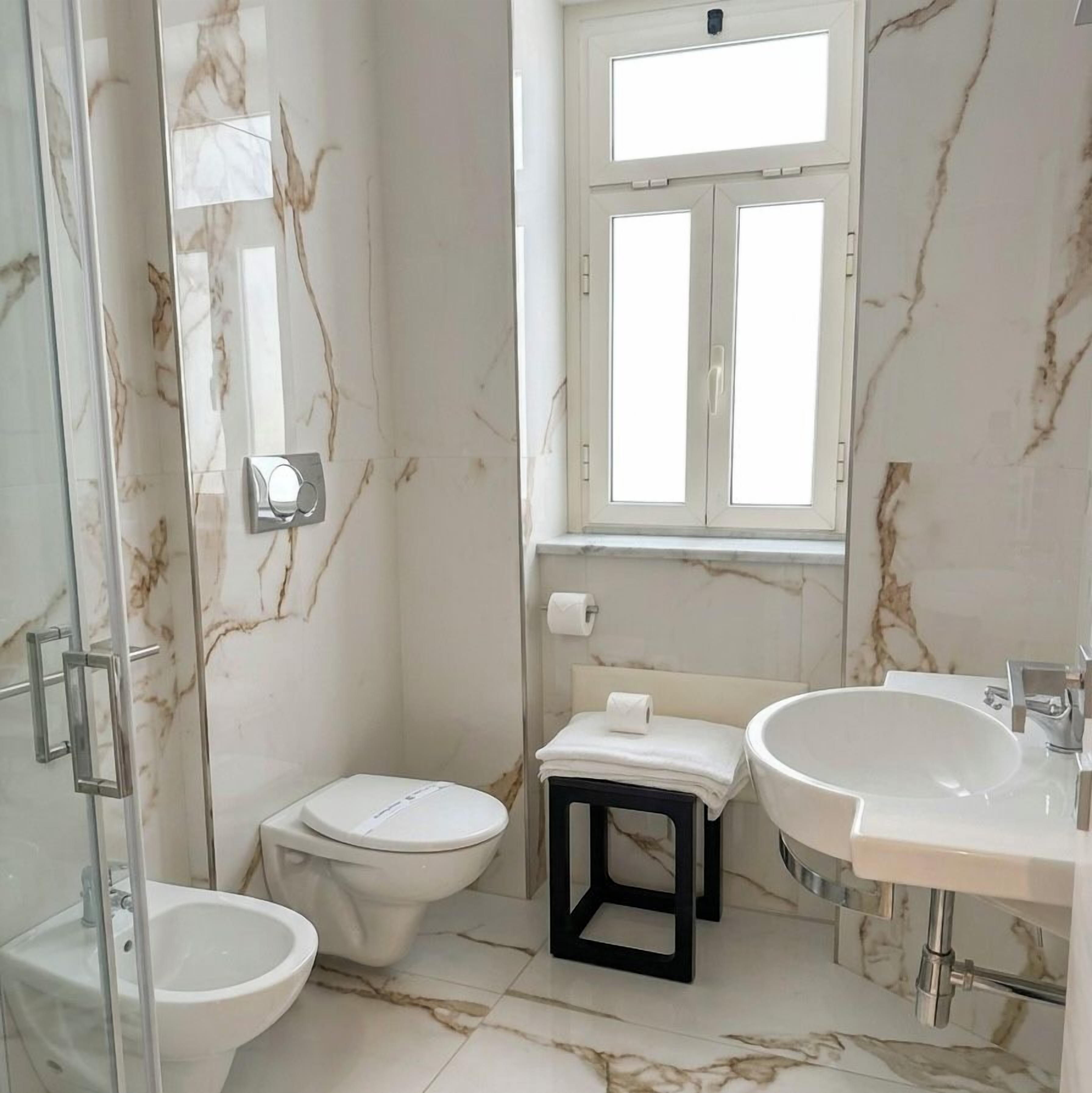 Une salle de bain comprenant une douche à parois de verre, des toilettes, un bidet et un lavabo.
