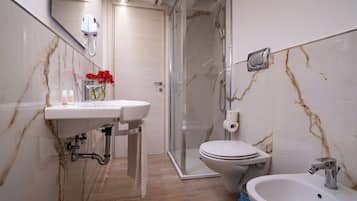 Un baño con lavamanos, inodoro y ducha de mármol.
