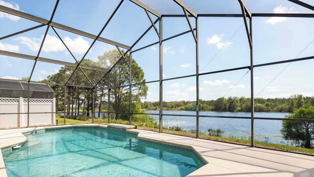 Una piscina con vistas despejadas a un lago y árboles al fondo.