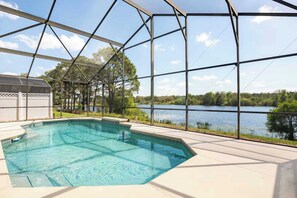A swimming pool with a clear view of a lake and trees in the background. - Theme Park Days & Sunshine Stays (Kissimmee)