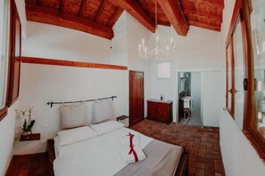 A bedroom with a wooden ceiling, a chandelier, a bed with white linens, a nightstand, and a potted plant. - Casa Sophia 4+1 beds (Vicchio)