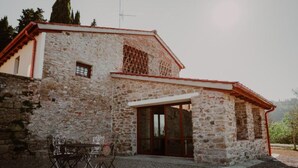 Ein Gebäude aus Stein mit rotem Dach, Glastür und einem Weg von Kies.