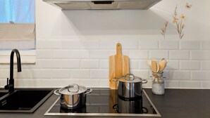 Een moderne keuken met een roestvrijstalen afzuigkap, een zwart inductiekookplaat, een spoelbak en een houten snijplank.