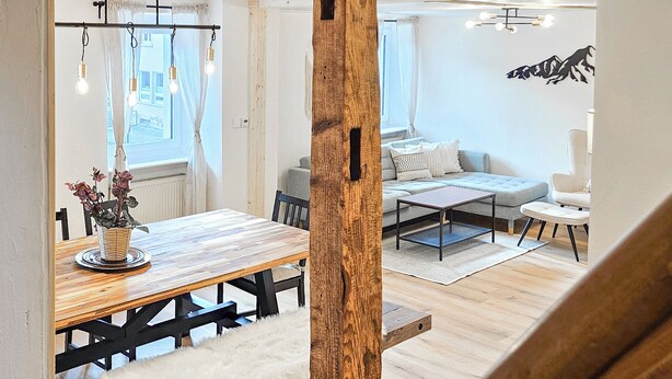 Een moderne woonkamer met een houten eettafel, een bank en een salontafel.