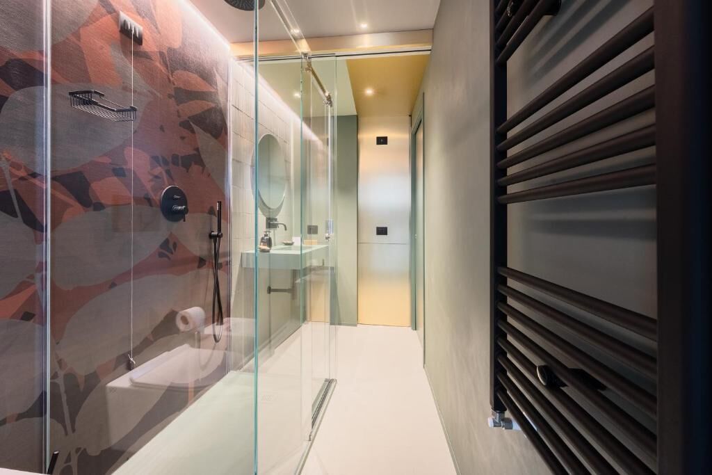 A modern bathroom with a glass enclosure, a shower, a sink, and a toilet.