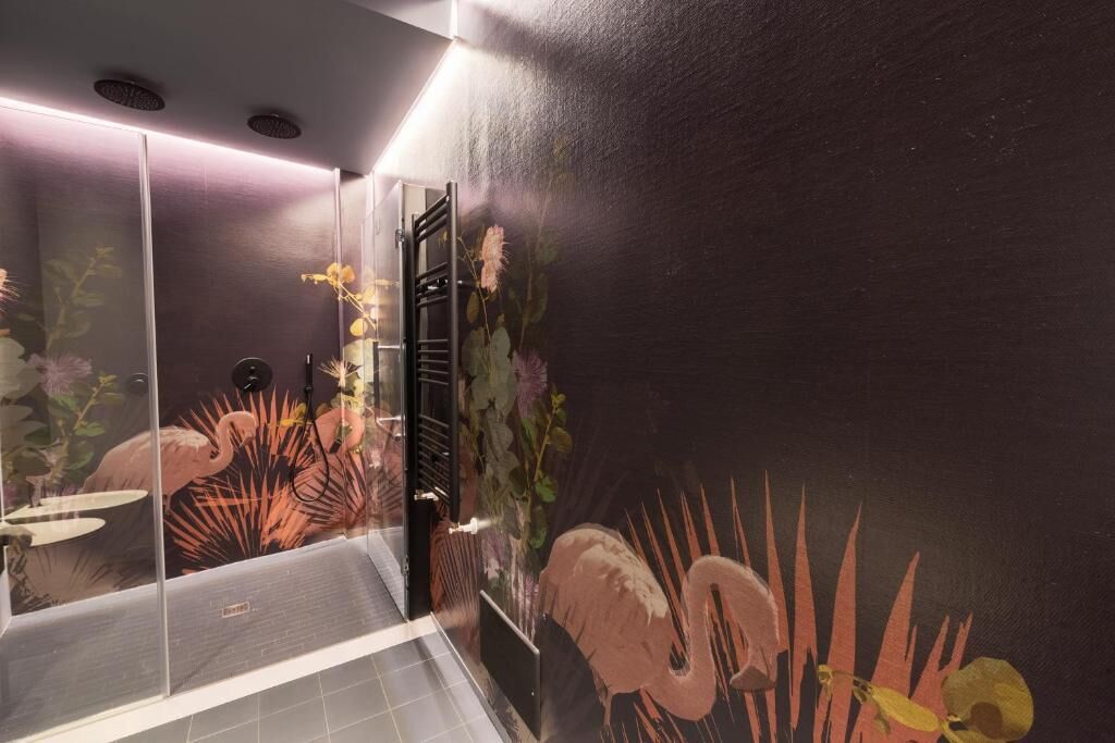 Une salle de bain avec un mur de couleur sombre, une douche en verre et une fresque murale à motifs floraux.