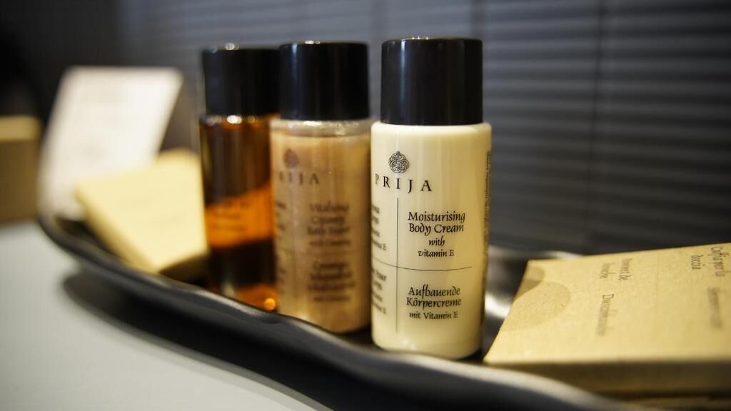A tray with three bottles of body cream and a bar of soap.