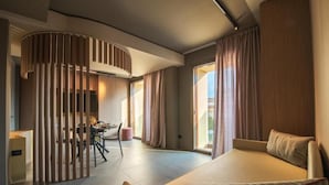 A modern hotel room with a large bed, a dining area, and a view of the outdoors. - Dimora San Girolamo (Marsala)