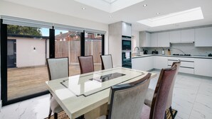 A modern kitchen with white cabinets, a built-in oven, and a large window.