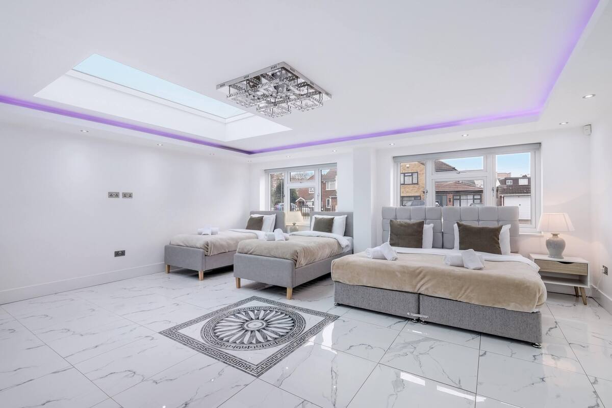 A modern bedroom with a skylight, two beds, a large window, and a marble floor.