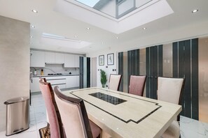 A modern dining area with a large table, chairs, and a view of the kitchen. - Stunning 5 Bedroom, 3 Bathroom Home in Windsor (Windsor)