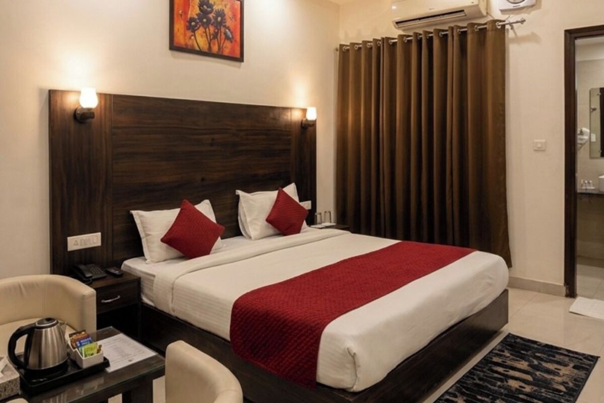 A hotel room with a bed, bedside table, chair, and a ceiling fan.